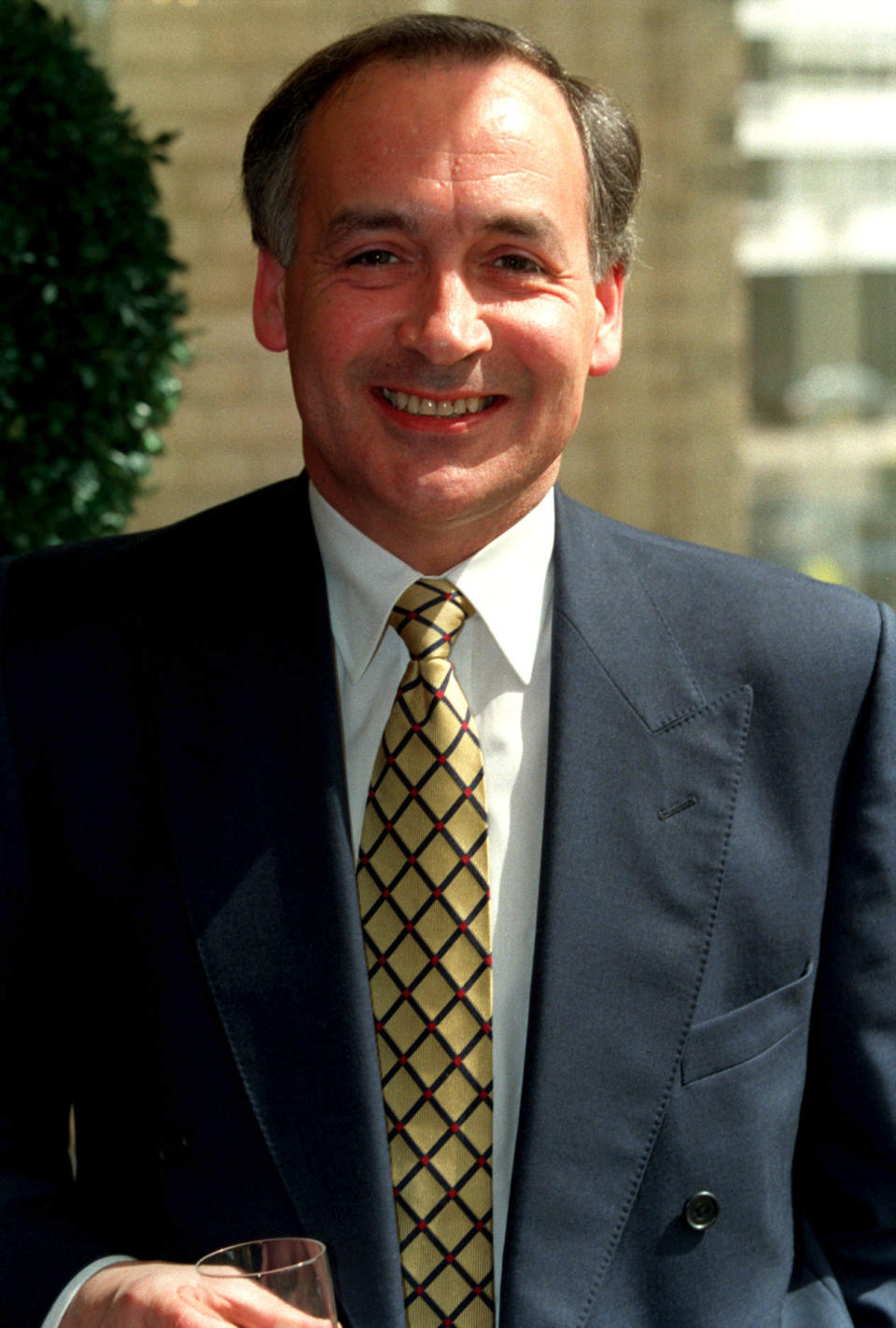 Alastair Stewart wearing a yellow tie and suit