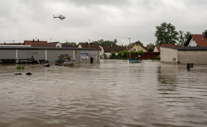 A police helicopter flies over a flooded residential area.  The region has been flooded due to recent heavy rainfall.  Stefan Puchner/dpa