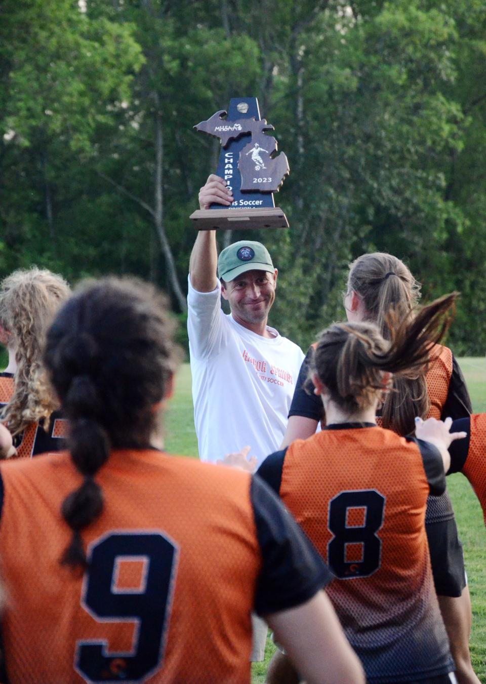 Harbor Springs head coach Aaron Riley hands the district championship trophy off to his team Friday night.