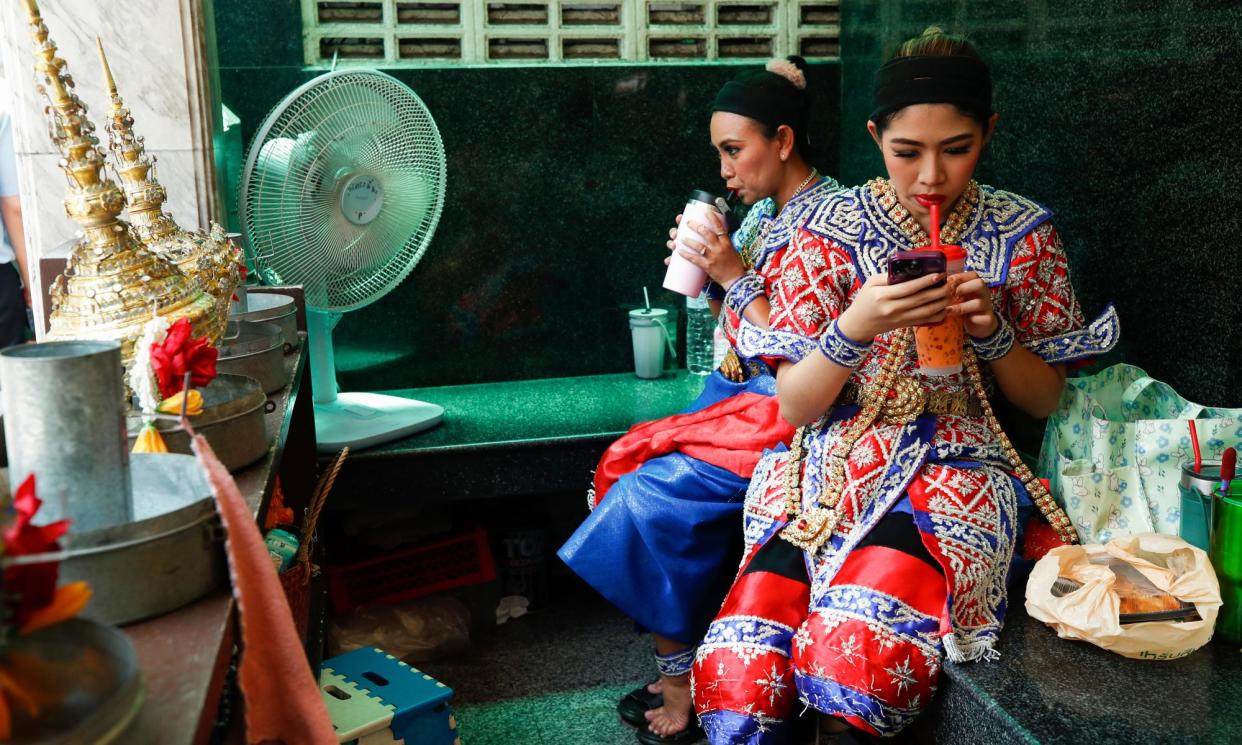<span>Thai dancers keep cool with cold drinks and a fan during the heatwaves in Thailand, where 30 people have died from heatstroke this year.</span><span>Photograph: Rungroj Yongrit/EPA</span>