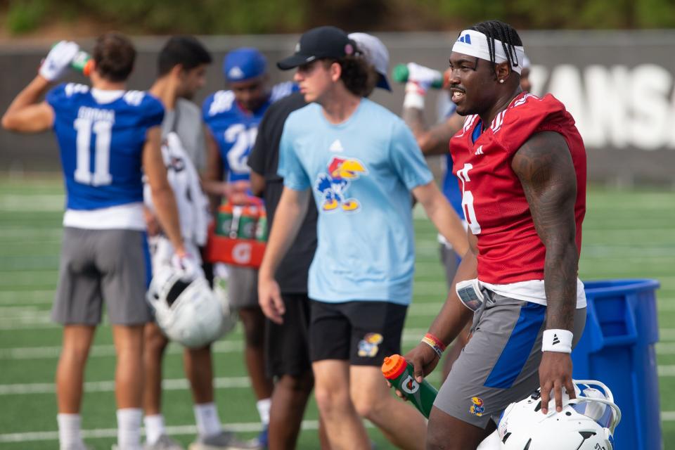 Kansas junior quarterback Jalon Daniels (6) takes a water break with teammates during a fall camp practice on Aug. 1.