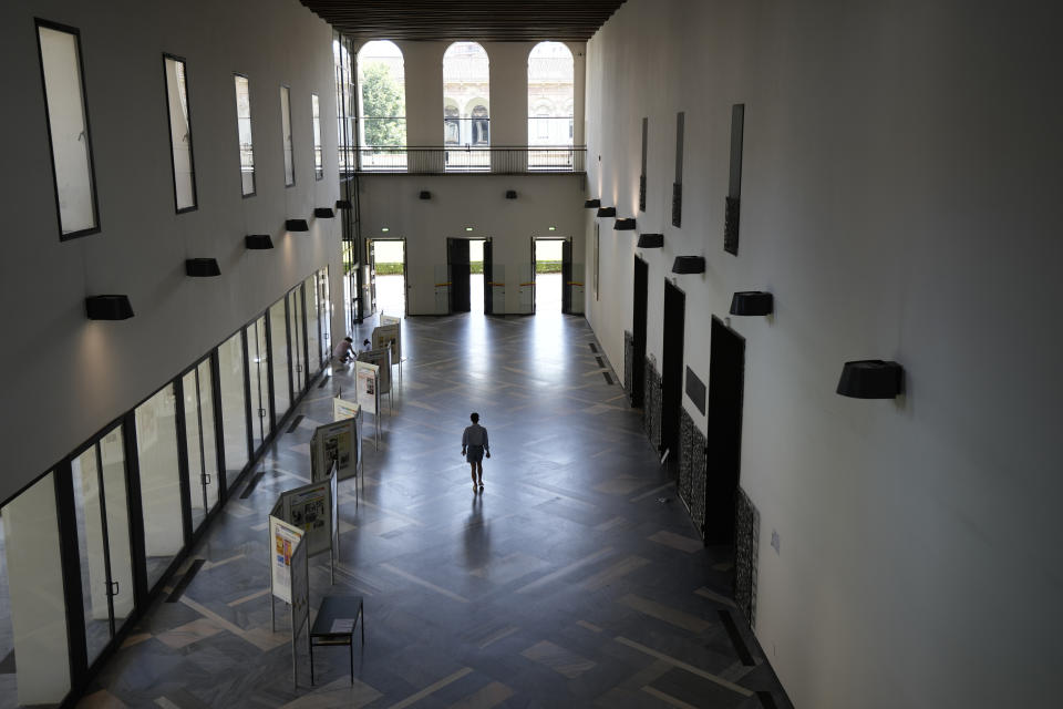 A person walks along a hallway of Milan's Statale University, northern Italy, Monday, June 21, 2021. Backed by 261 billion euros from the EU and Italian government, the country’s recovery plan calls for a top-to-bottom shakeup of a major industrial economy long hampered by red tape, a fear of change, and bureaucratic and educational inertia. Leading the charge is Premier Mario Draghi, the former head of the European Central Bank, who was tapped as head of a national unity government specifically for his economic expertise and institutional knowledge both in Italy and the EU. A key target is keeping more young Italians from taking their know-how abroad, a perennial issue in Italy, which has one of the lowest rates of university graduates in Europe and one of the largest brain drains. (AP Photo/Antonio Calanni)