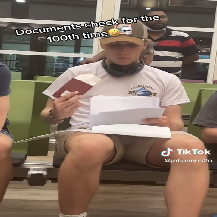 Man sitting at airport holding papers with caption 