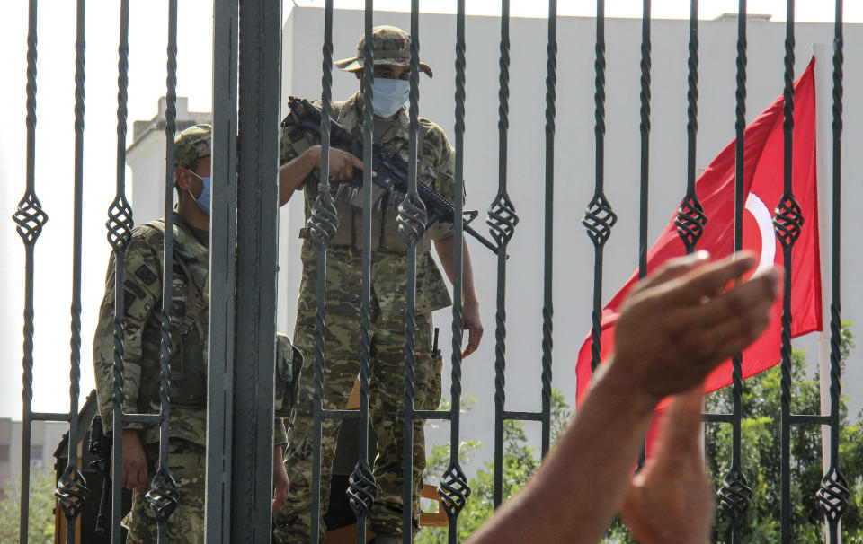 Tunisian soldiers guard the main entrance of the parliament as demonstrators gather outside the the gate in Tunis, Tunisia, Monday, July 26, 2021. Troops surrounded Tunisia's parliament and blocked its speaker from entering Monday after the president suspended the legislature and fired the prime minister following nationwide protests over the country's economic troubles and the government's handling of the coronavirus crisis. (AP Photo/Hedi Azouz)