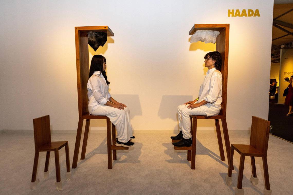 Two models sit in Maria Abravanic’s “Chairs for Human and Spirit Use” during the VIP opening of Design Miami in Miami Beach.