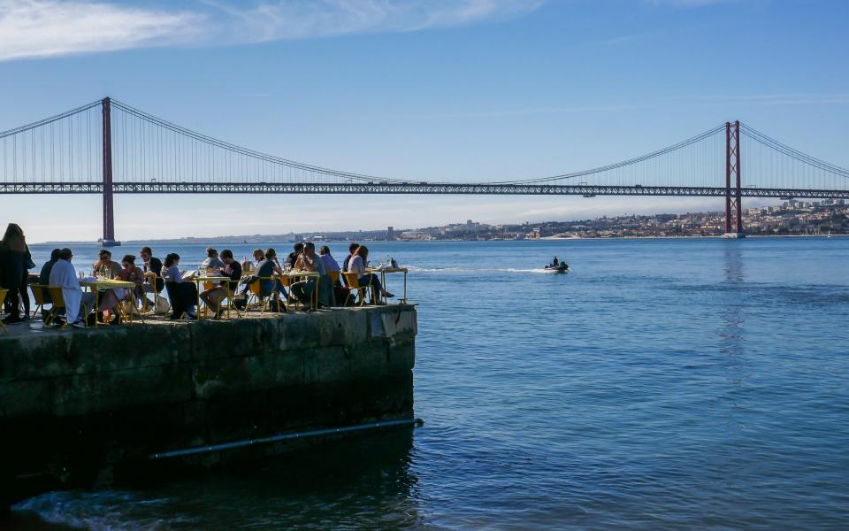 people on jetty out at sea overlooking lisbon bridge - BrasilNut1 /iStock Editorial 