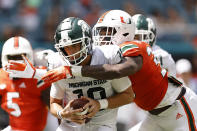 Miami defensive lineman Chantz Williams (33) sacks Michigan State quarterback Payton Thorne (10) during the first quarter of an NCAA college football game, Saturday, Sept. 18, 2021, in Miami Gardens, Fla. (AP Photo/Michael Reaves)