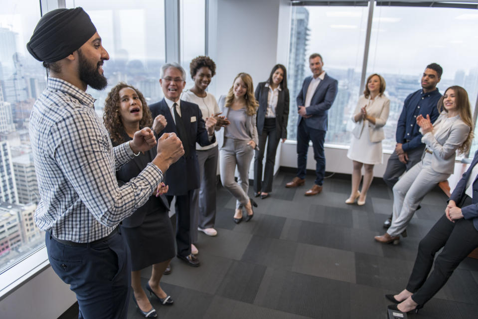 group of coworkers standing in a circle in a conference room