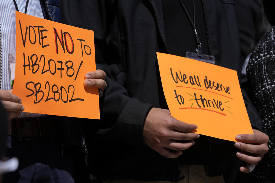 People hold signs during a news conference of the Tennessee Immigrant and Refugee Rights Coalition outside the state Capitol, Tuesday, March 19, 2024, in Nashville, Tenn. Members of the group came to the state Capitol to lobby legislators to vote against legislation that require local law-enforcement agencies to operate as if they have federal 287(g) agreements and a bill criminalizing transportation of undocumented immigrants. (AP Photo/George Walker IV)