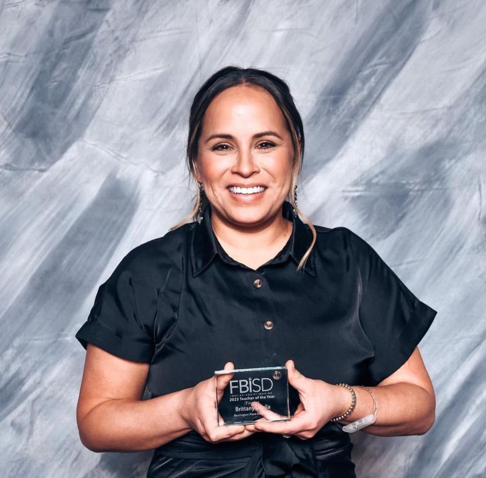 Brittany Davila smiles while holding her 2023 Teacher of the Year finalist plaque.