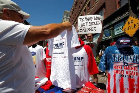 A man browses at Donald Trump merchandise as a protester stands by outside the Republican National Convention in Cleveland, Ohio, U.S., July 20, 2016. REUTERS/Andrew Kelly