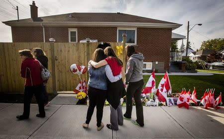 Workers from the St. Eugene Catholic Elementary School, where Cpl. Nathan Cirillo's son is enrolled, pay respects at a makeshift memorial in honour of Cpl. Cirillo, outside the family home in Hamilton, October 24, 2014. REUTERS/Mark Blinch