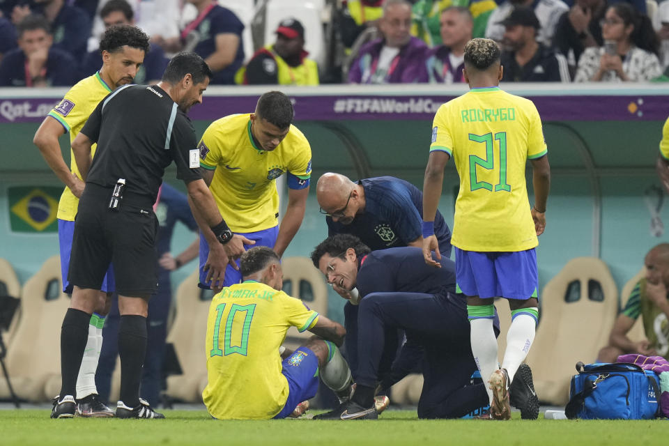 Brazil's Neymar, bottom, is treated by members of his team during the World Cup group G soccer match between Brazil and Serbia, at the Lusail Stadium in Lusail, Qatar, Thursday, Nov. 24, 2022. (AP Photo/Aijaz Rahi)