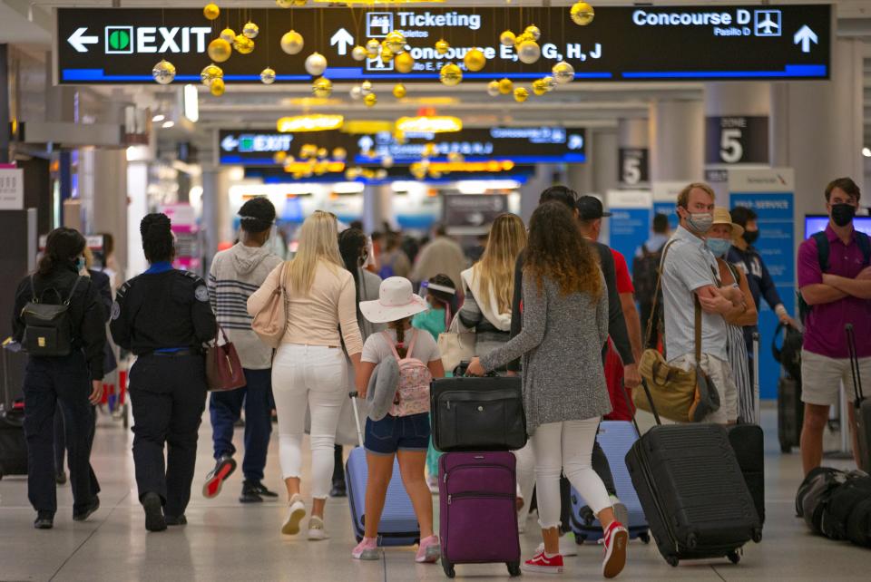 Travelers wearing protective face masks walk through Concourse D at the Miami International Airport on Nov. 22, 2020. With the coronavirus surging out of control, the nation's top public health agency pleaded with Americans not to travel for Thanksgiving and not to spend the holiday with people from outside their household.