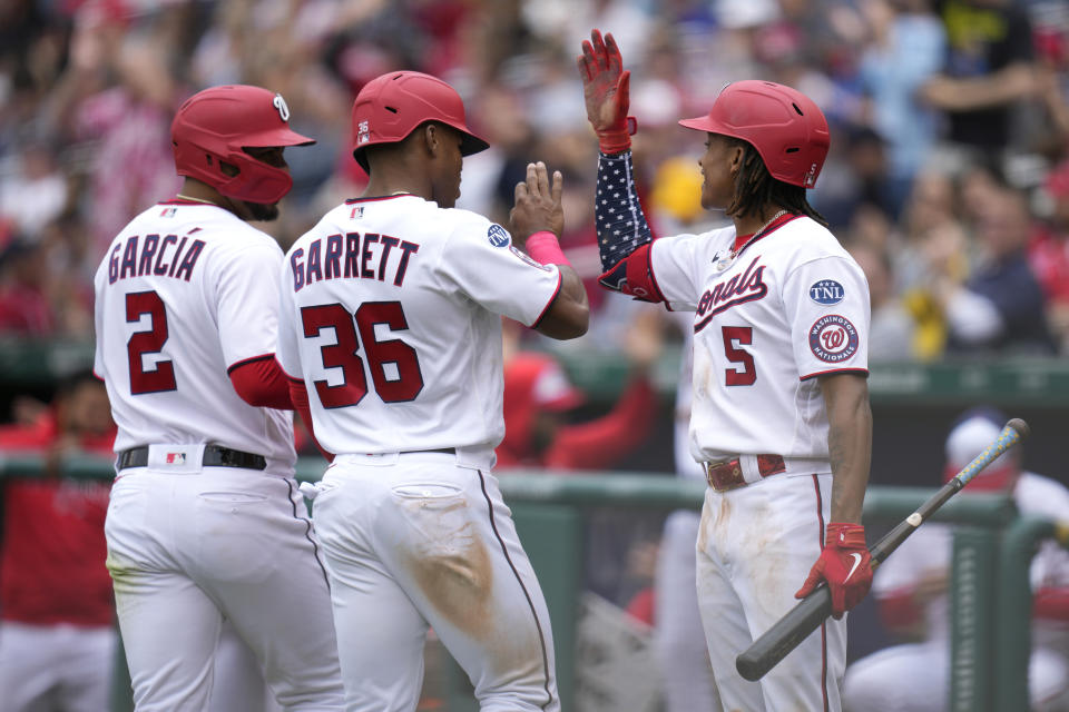 Washington Nationals' CJ Abrams, right, high-fives teammates Luis Garcia and Stone Garrett after they scored on Riley Adams' double in the fourth inning of the first baseball game of a doubleheader against the Pittsburgh Pirates, Saturday, April 29, 2023, in Washington. (AP Photo/Patrick Semansky)