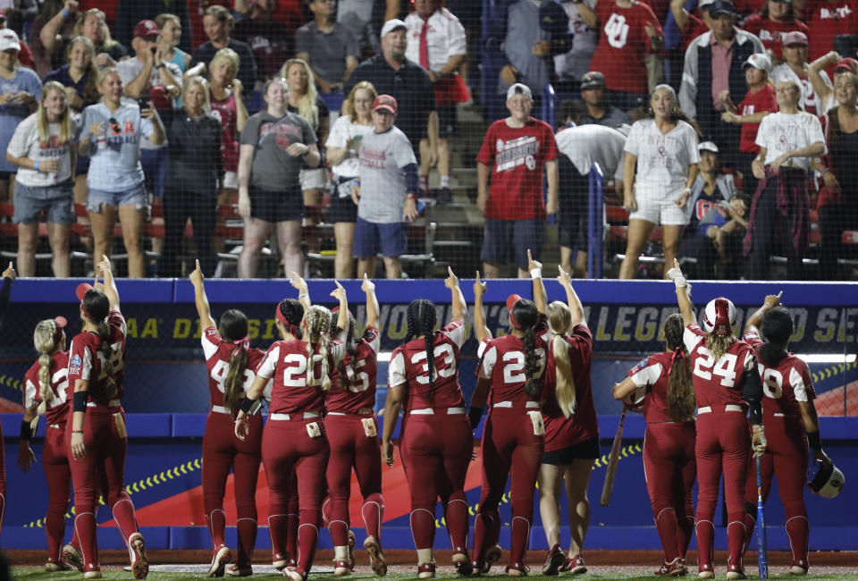 Oklahoma fans stand as players gesture to them during the fifth inning of an NCAA Women's College World Series softball game against UCLA, Saturday, June 5, 2021, in Oklahoma City. (AP Photo/Alonzo Adams)