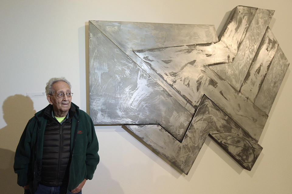 FILE - U.S. artist Frank Stella stands in front of one of his works at an exhibition devoted to him in Warsaw, Poland, Feb. 18, 2016. Stella, a painter, sculptor and printmaker whose constantly evolving works are hailed as landmarks of the minimalist and post-painterly abstraction art movements, died Saturday, May 4, 2024, at his home in Manhattan. He was 87. (AP Photo/Czarek Sokolowski, File)