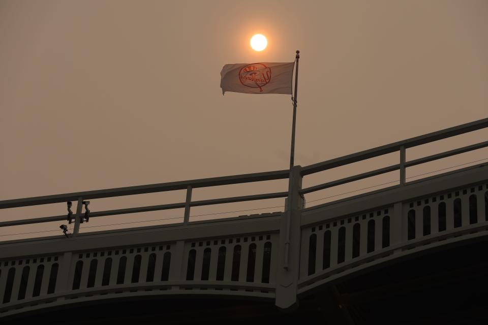 A Yankees flag flaps in the wind in front of the sun which is obscured by haze at Yankee Stadium after a game between the New York Yankees and the Chicago White Sox was rescheduled due to poor air quality on June 7, 2023. 