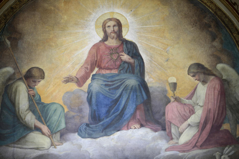 A religious painting depicts Jesus seated on a throne with a glowing halo, flanked by two kneeling angels, one holding a staff and the other a chalice