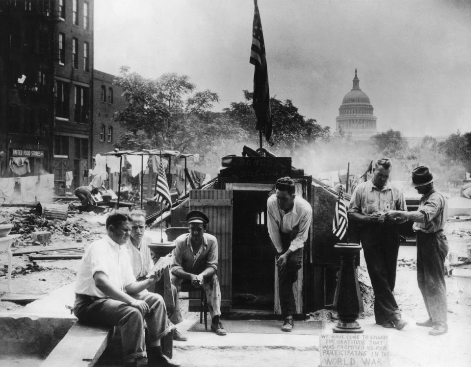 In this 1932 photograph, a group of men huddle near the ruins of their Bonus Army camp. <a href="https://www.gettyimages.com/detail/news-photo/bonus-army-in-washington-d-c-united-states-washington-news-photo/535780959?phrase=bonus%20army&adppopup=true" rel="nofollow noopener" target="_blank" data-ylk="slk:Photo12/Universal Images Group via Getty Images;elm:context_link;itc:0;sec:content-canvas" class="link ">Photo12/Universal Images Group via Getty Images</a>