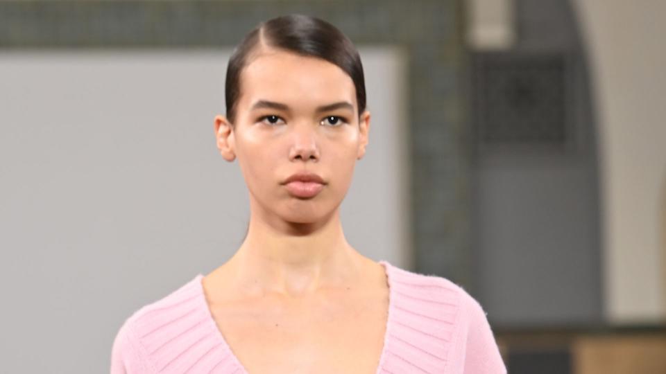  A model walks the runway at the JW Anderson show during London Fashion Week wearing a pink v neck cardigan adorned with yellow flowers