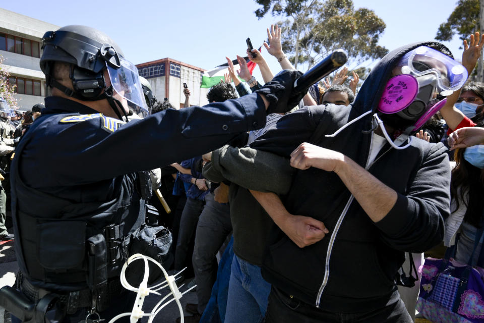 A Pro-Palestinian protester is hit with a baton by a police officer at UC San Diego, Monday, May 6, 2024, in San Diego. Police cleared a campus encampment in the early morning Monday. (AP Photo/Denis Poroy)
