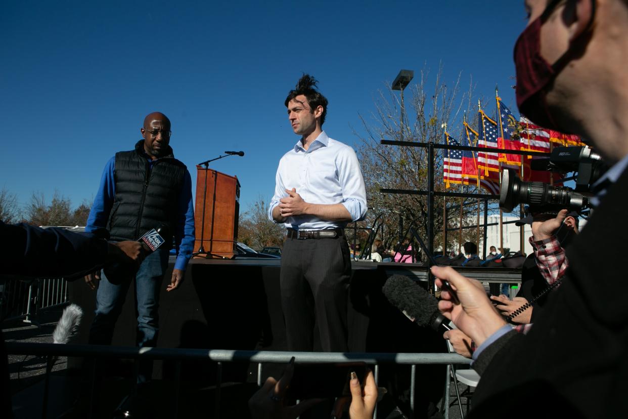 <p>US Senate candidates Raphael Warnock (L) and Jon Ossoff take questions from the press during an outdoor drive-in rally on December 5.</p> (Getty Images)