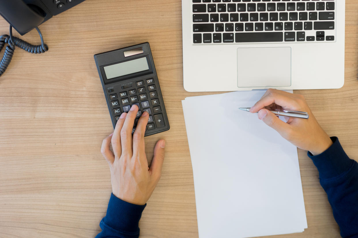 close up top view of man hand press on calculator counting calculating about monthly expense and writing list to paper ,money management concept