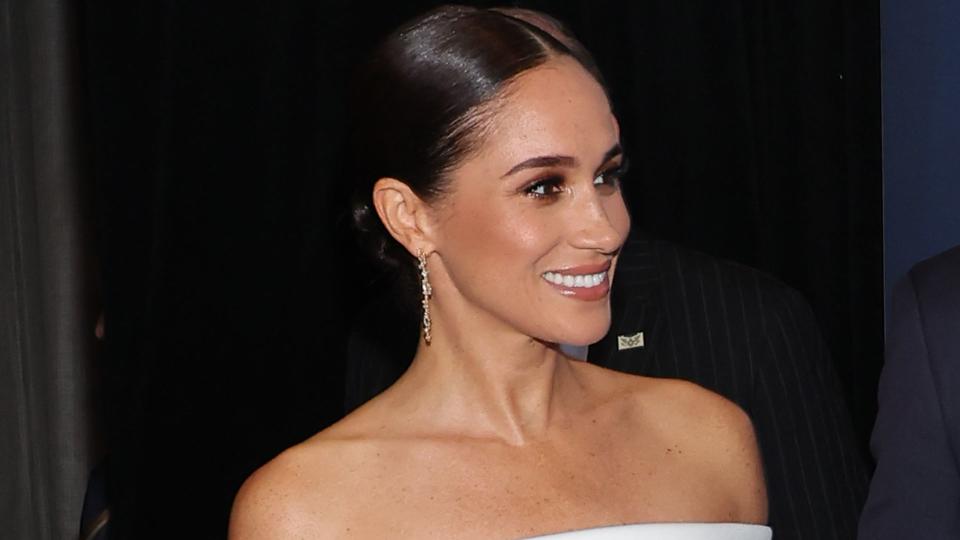 The Duchess of Sussex in a white off-the-shoulder dress and Prince Harry in a suit