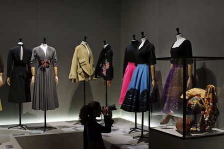 A visitor takes picture of vintage dresses by designers Jacques Fath, Pauline Trigere, Gres, Pierre Balmain, Givenchy and Schiaparelli presented in the exhibition "Les Annees 50, La mode en France" (The 50s. Fashion in France, 1947-1957) at the Palais Galliera fashion museum in Paris, July 10, 2014. REUTERS/Benoit Tessier