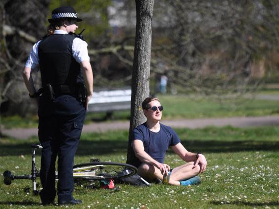 Police speak to people sitting in Greenwich Park in London, 5 April (EPA)