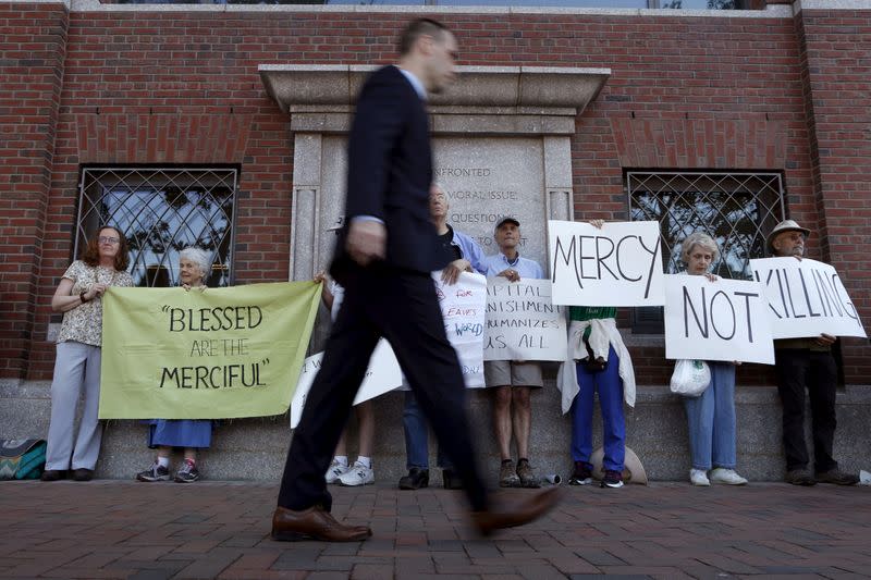 FILE PHOTO: A pedestrian walks past death penalty protesters before the formal sentencing of convicted Boston Marathon bomber Dzhokhar Tsarnaev at the federal courthouse in Boston