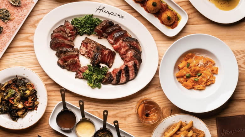 steak, pasta and sides on white harper's logo plate