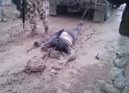 A still image made from undated footage posted on the YouTube social media website and believed to be shot in Anbar province shows a dead man, suspected of being a member of the al Qaeda-linked Islamic State in Iraq and the Levant (ISIL) group, tied to the back of an Iraqi military vehicle before the vehicle is driven away, as men in Iraqi military uniforms stand close by. REUTERS/YouTube