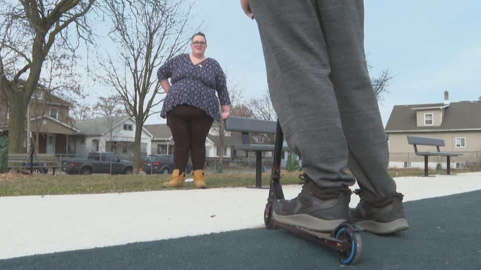 Jenna Beattie stands at a park with her son who was robbed in Windsor on February 11. The 15-year-old robbery victim spoke with CBC News under condition that his face not be shown and his name not be published.  (Meg Roberts/CBC - image credit)