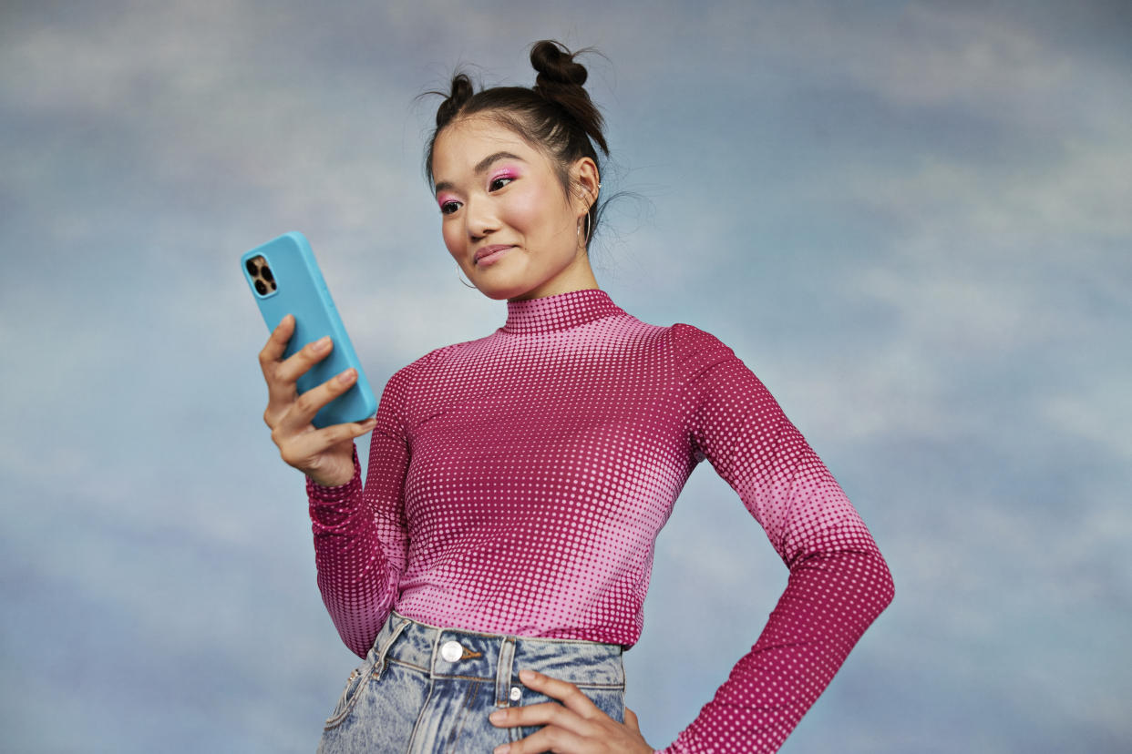 Girl using mobile phone against colored background