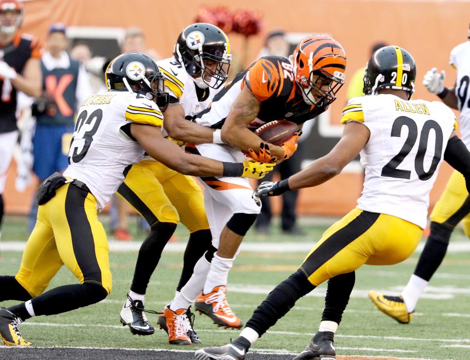 Cincinnati Bengals wide receiver Marvin Jones (82) is stopped by Pittsburgh Steelers free safety Mike Mitchell (23) and defensive back Ross Cockrell (31) at Paul Brown Stadium Sunday December 13, 2015. The Bengals lost 33-20.