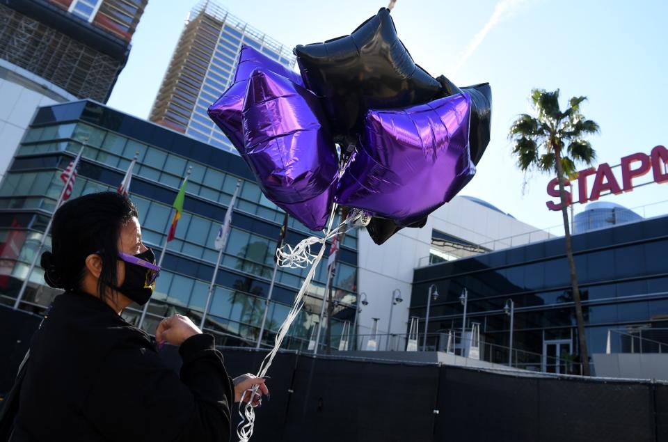 Josie Alavarez does the sign of the cross before releasing balloons on the one-year anniversary of Kobe Bryant's death.