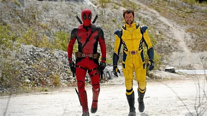 deadpool and wolverine walk down a sandy road