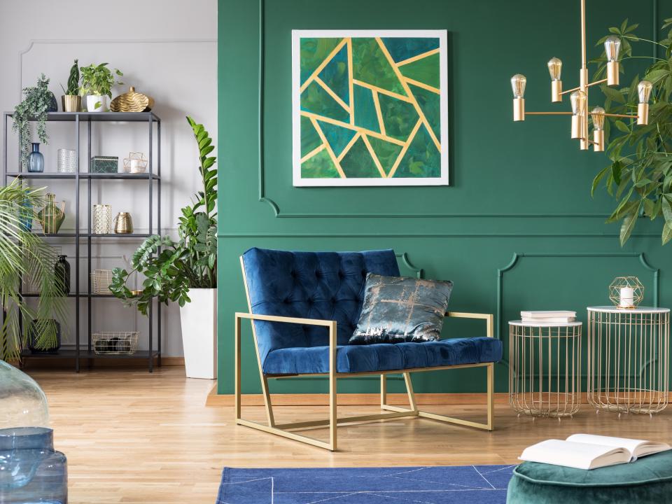 living room with green walls, blue velvet chair and plants