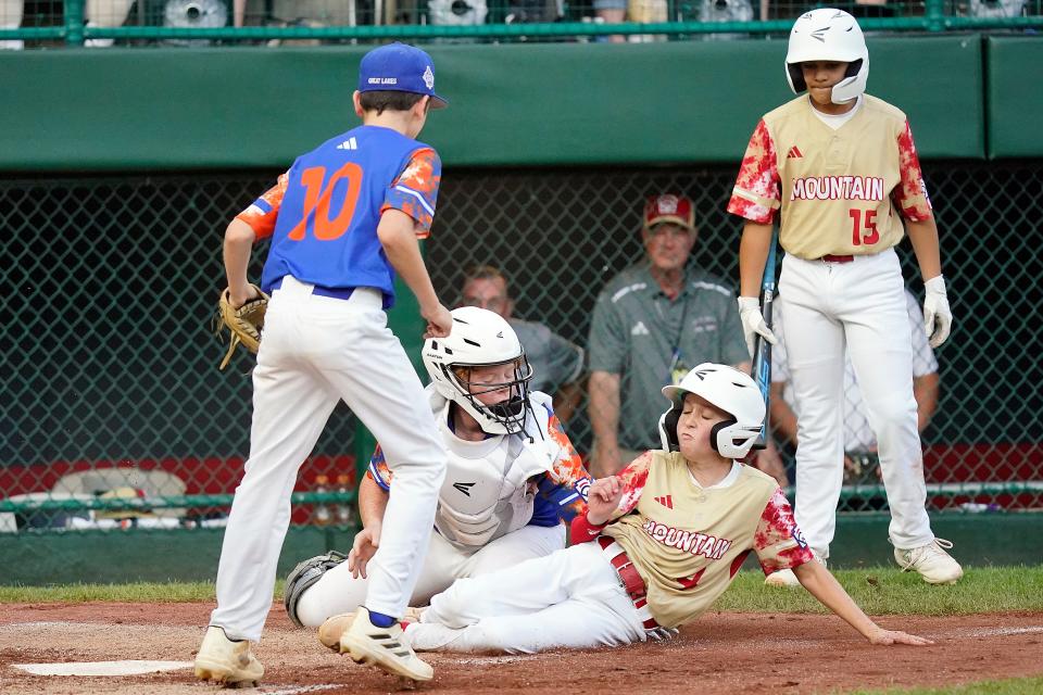 New Albany, Ohio, catcher Hunter Sayre, center, tags out Henderson, Nev.'s Mason Walther (4) who was attempting to score on a passed ball as New Albany, Ohio, pitcher Beau Spangler, left, watches during the third inning of a baseball game at the Little League World Series tournament in South Williamsport, Pa., Saturday, Aug. 19, 2023.