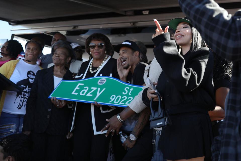 Family, friends, and politicians hold the new Eazy St. sign while some sing along to the song Boyz N The Hood.