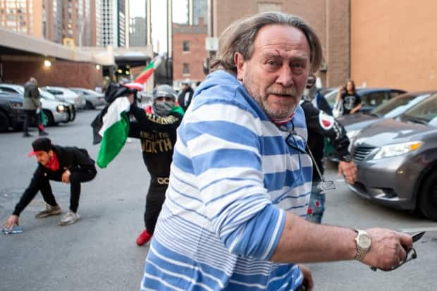 New images appear to show the man, believed to be the victim of an assault by pro-Palestinians in Toronto on Saturday, was holding what looks like a knife during the altercation. (Chris Young/Canadian Press - image credit)