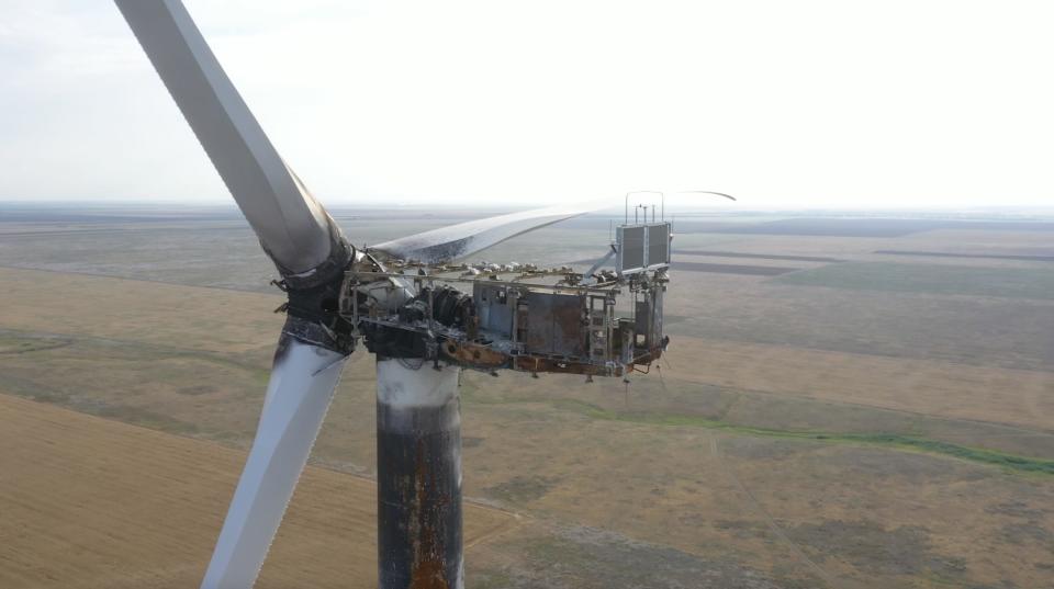 A medium shot of a damaged wind turbine that appears to have suffered a fire.