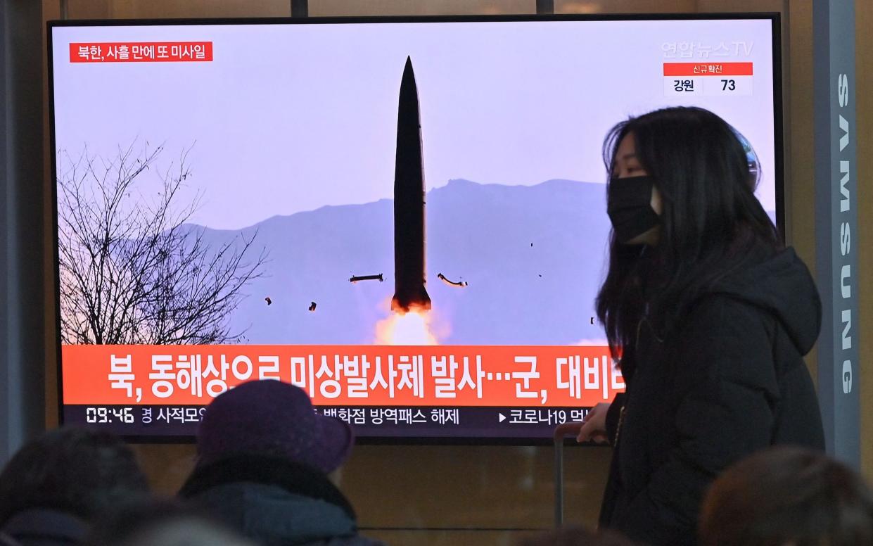 A woman walks past a television screen showing a news broadcast with file footage of a North Korean missile test, at a railway station in Seoul on January 17, 2022, - Jung Yeon Je/AFP