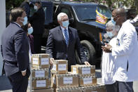 Vice President Mike Pence, center, speaks to staff members after delivering personal protective equipment to the Westminster Baldwin Park, Wednesday, May 20, 2020, in Orlando, Fla., as part of the initiative to deliver PPE to more than 15,000 nursing homes across America. Looking on is Florida Gov. Ron DeSantis, left. Pence is also scheduled to participate in a roundtable discussion with hospitality and tourism industry leaders to discuss their plans for re-opening during the coronavirus outbreak. (AP Photo/Chris O'Meara)