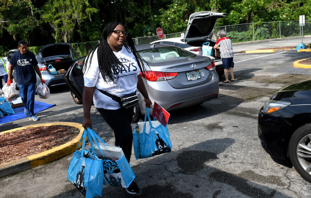 Volunteers load bags of food for the needy into cars at a food distribution event sponsored by the Second Harvest Food Bank of Central Florida and Orange County at St. John Vianney Church in Orlando, Florida. (Photo by Paul Hennessy/SOPA Images/LightRocket via Getty Images)