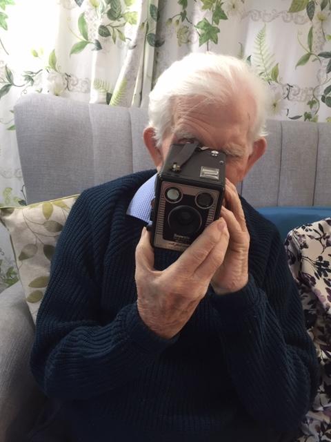 A care home resident using a camera from one of the memory boxes