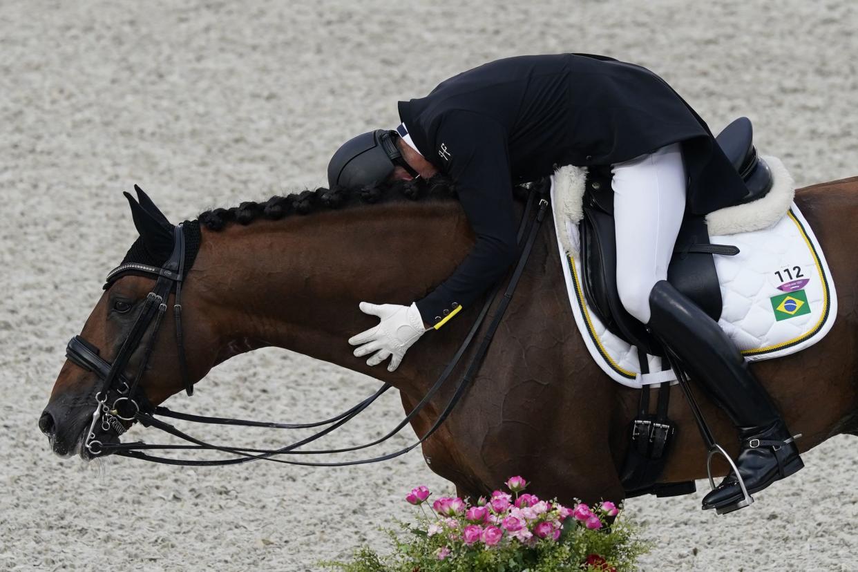 Brazil's Joao Victor Marcari Oliva, hugs Escorial Horsecampline as he celebrates after competing during the dressage Grand Prix competition at Equestrian Park the 2020 Summer Olympics, Saturday, July 24, 2021, in Tokyo, Japan.