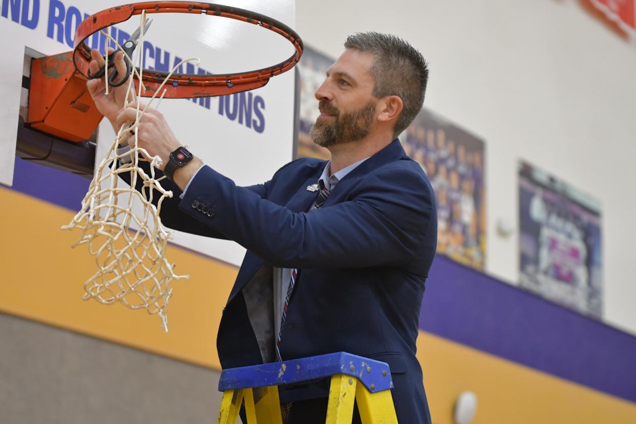 Evangel basketball coach Bert Capel cuts down the nets after winning a NAIA regional title.